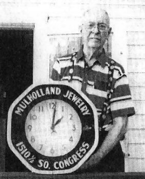 Cecil Mulholland holding his jewelry store sign