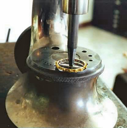 using the staking set to install the balance wheel onto the new balance staff for the watch