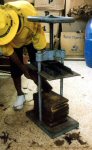 The cigars are placed in wooden boxes under a press
